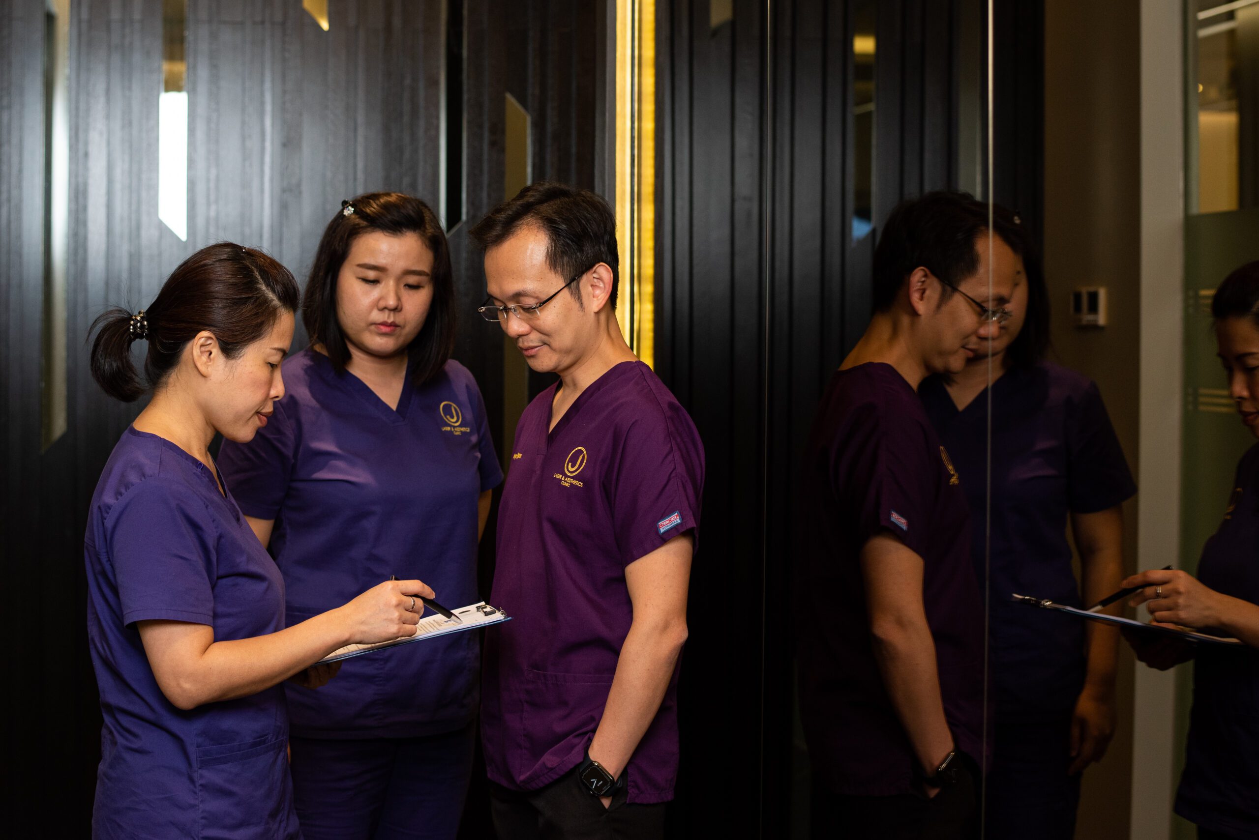 teleconsultation and aesthetic doctor ngiam juzheng with 2 team members near the mirror dressed in clinic uniforms