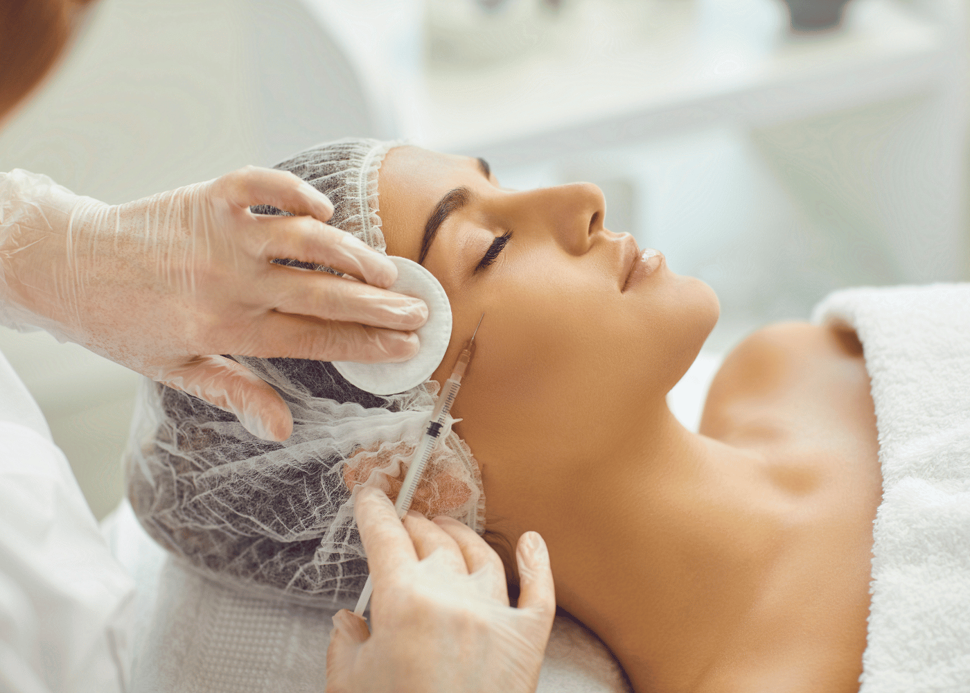 lady wearing a shower cap and robe having filler injection on face at aesthetic clinic in singapore