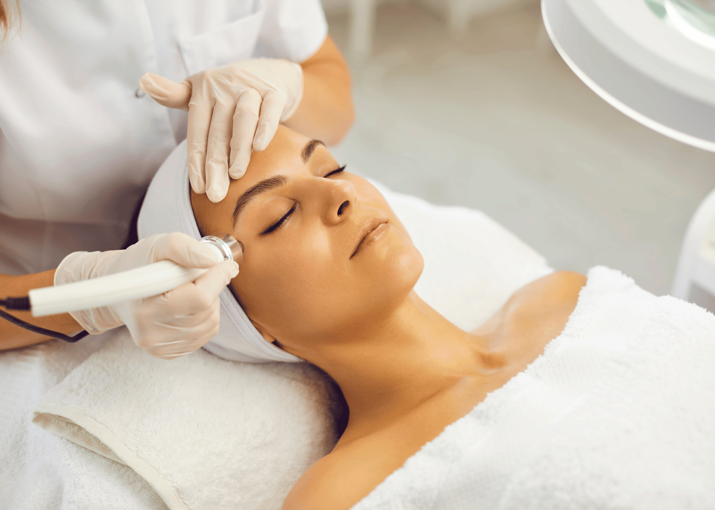 lady wearing a hair band and robe having laser treatment on face